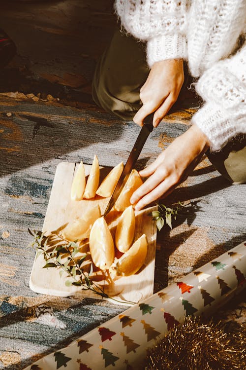 A Person Slicing a Fruit on a Wooden Chopping Board