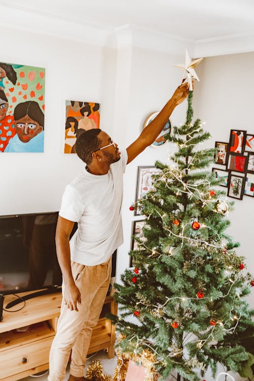 A Man Putting a Star on a Christmas Tree
