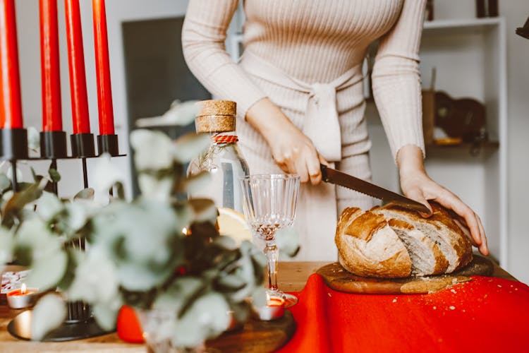 A Woman Slicing A Loaf Of Bread On A Chopping Board