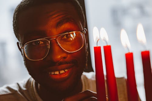A Close-up Shot of a Man Wearing Eyeglasses Near the Lighted Candles