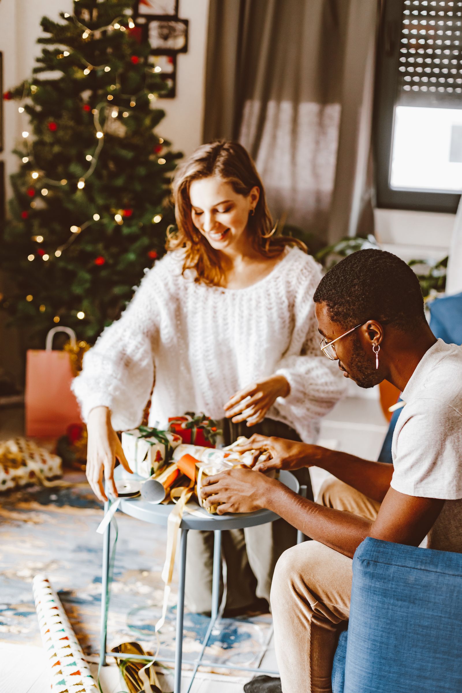 Two people wrapping Christmas gifts together at a table.