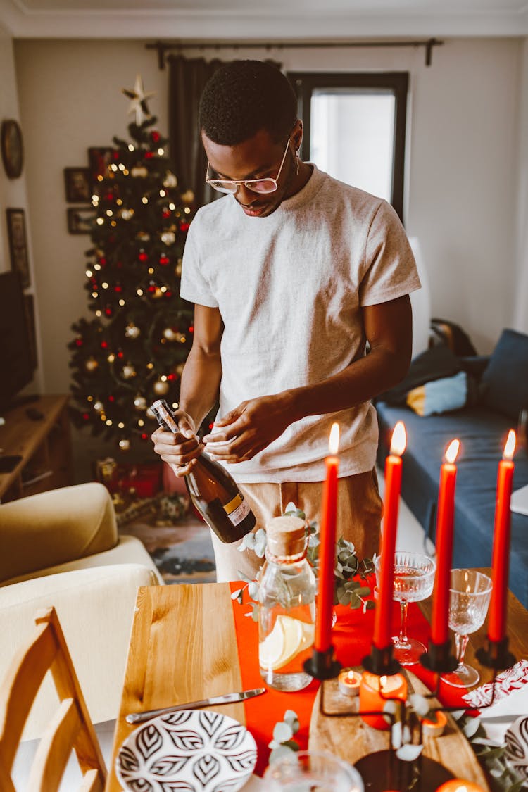 A Man By The Table Holding A Bottle Of Wine