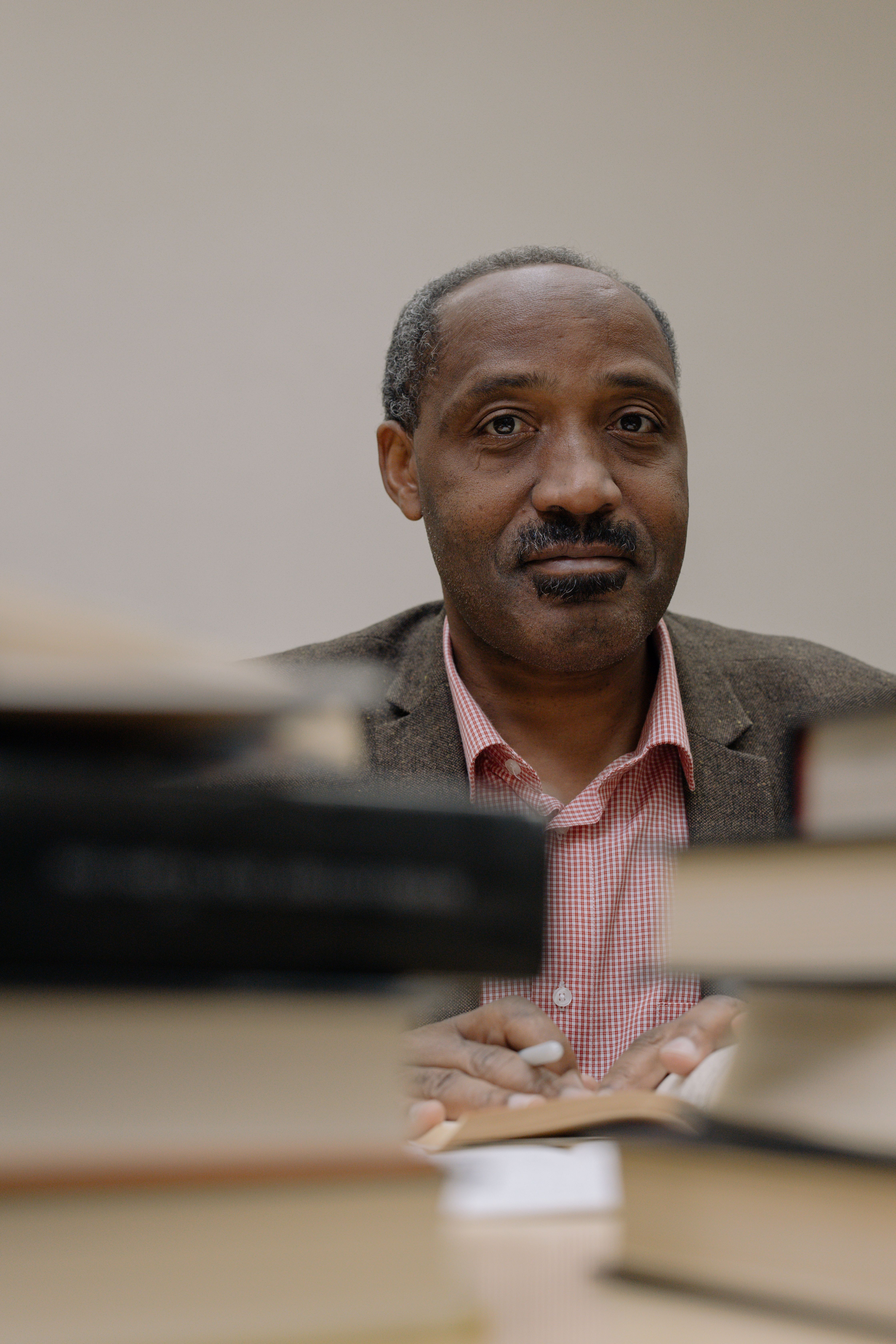 African American man surrounded by books in a library, showcasing education and wisdom.
