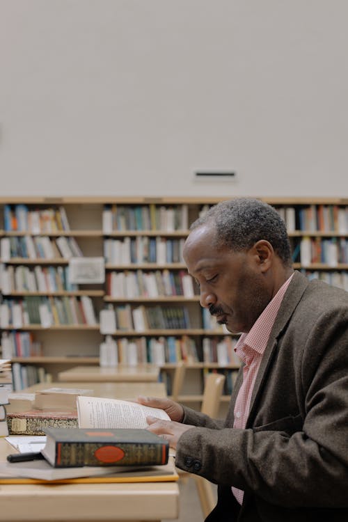 Man in Pink Dress Shirt Reading Book