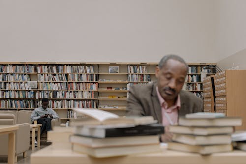 Man in Gray Dress Shirt Sitting Beside Brown Wooden Table