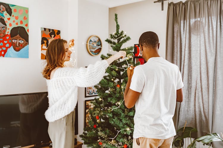 Couple Decorating Christmas Tree At Home