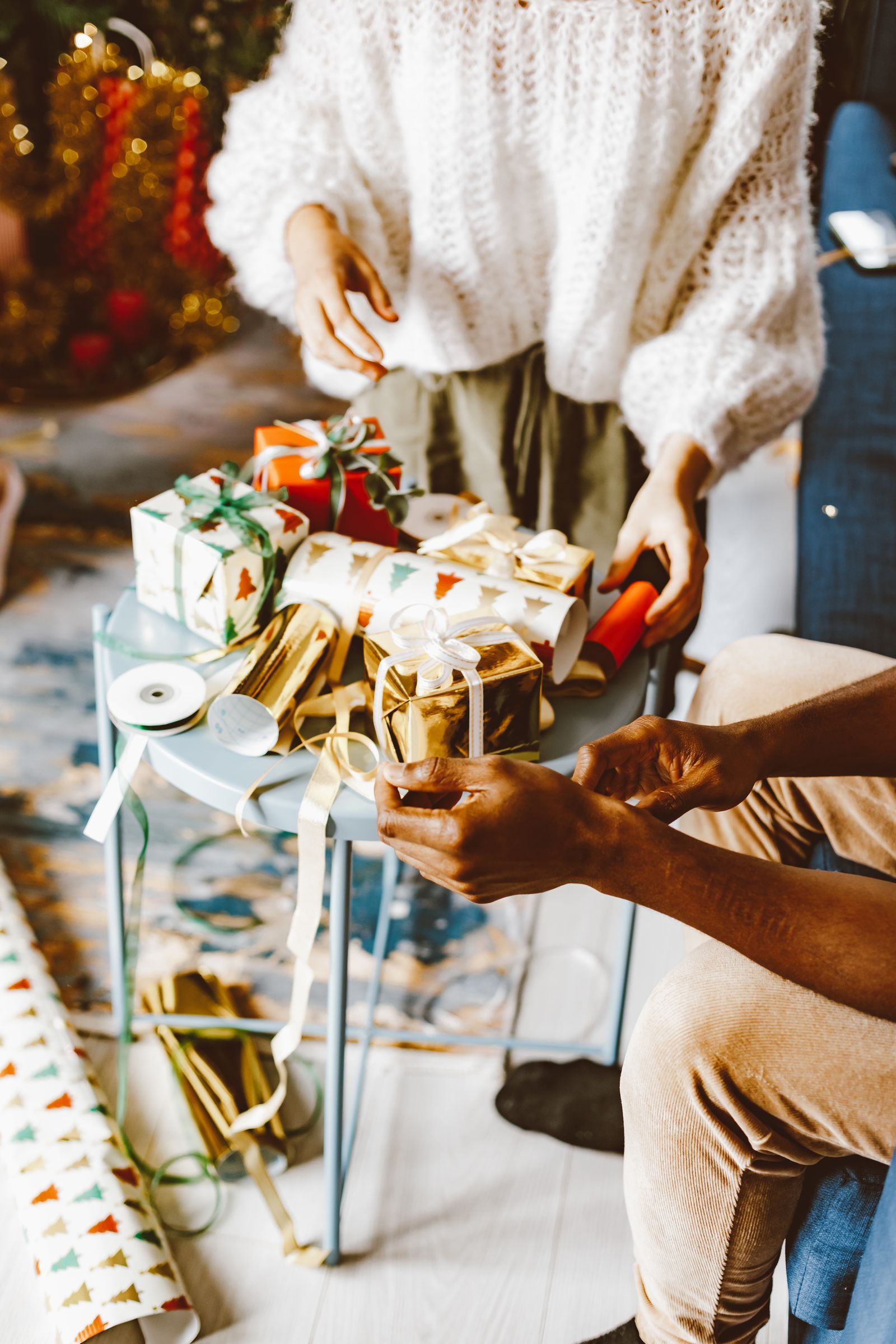 Two people wrapping Christmas presents at a table