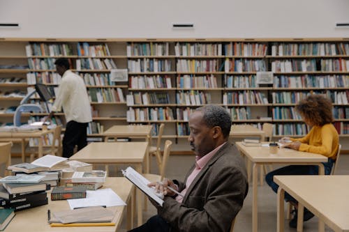 Free Man in Brown Coat Reading Book Stock Photo