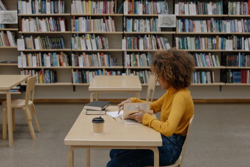 Free A focused woman reading in a library, highlighting education and learning. Stock Photo