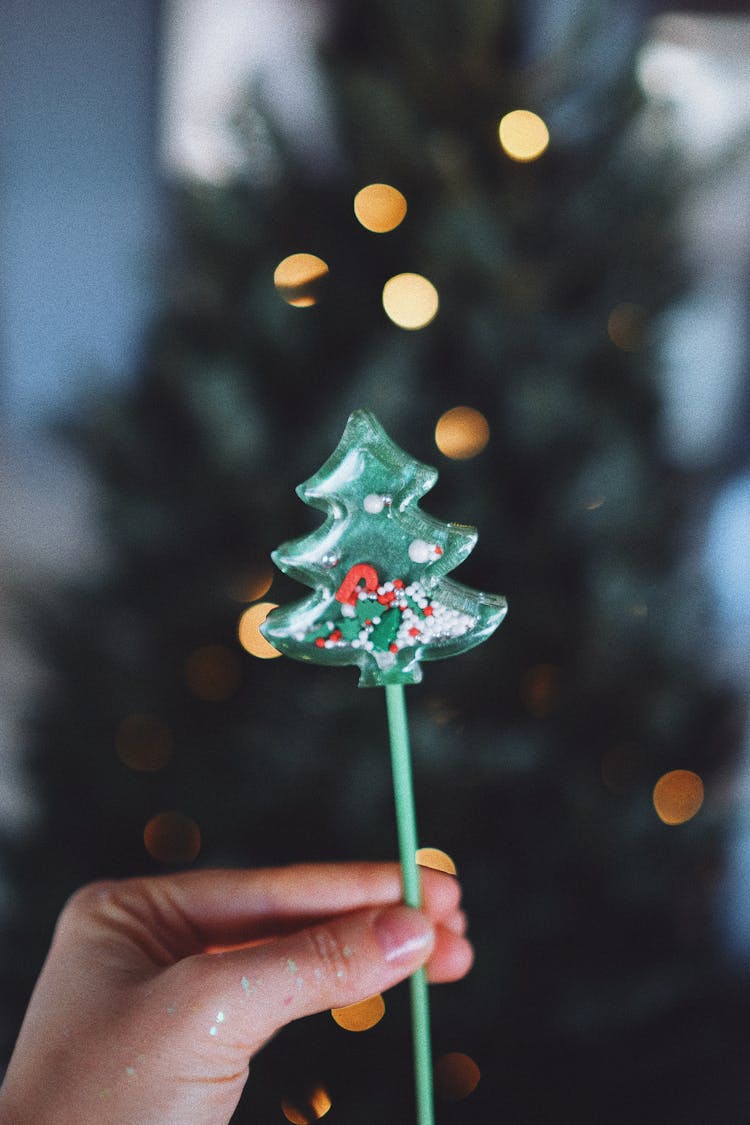 A Person Holding A Christmas Tree Lollipop