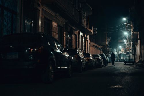 Free Dramatic nighttime street view in Qena, Egypt with lights and parked cars. Stock Photo