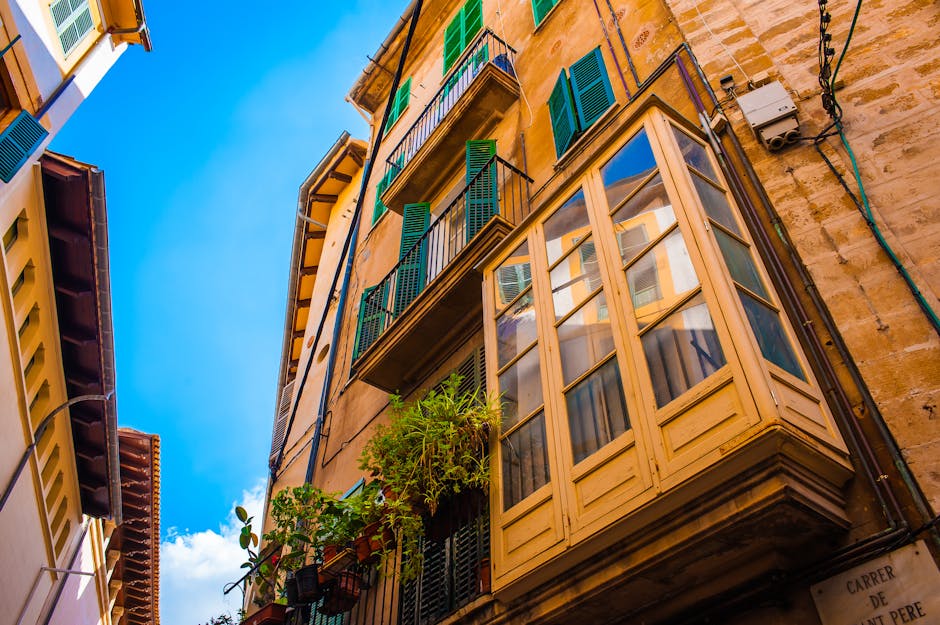Una vista vibrante desde un ángulo bajo de edificios mediterráneos con persianas coloridas y balcones.