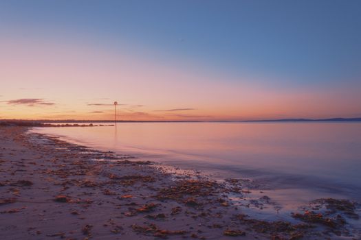 Serene seascape at sunset with calm water and colorful sky at Christchurch beach, UK.