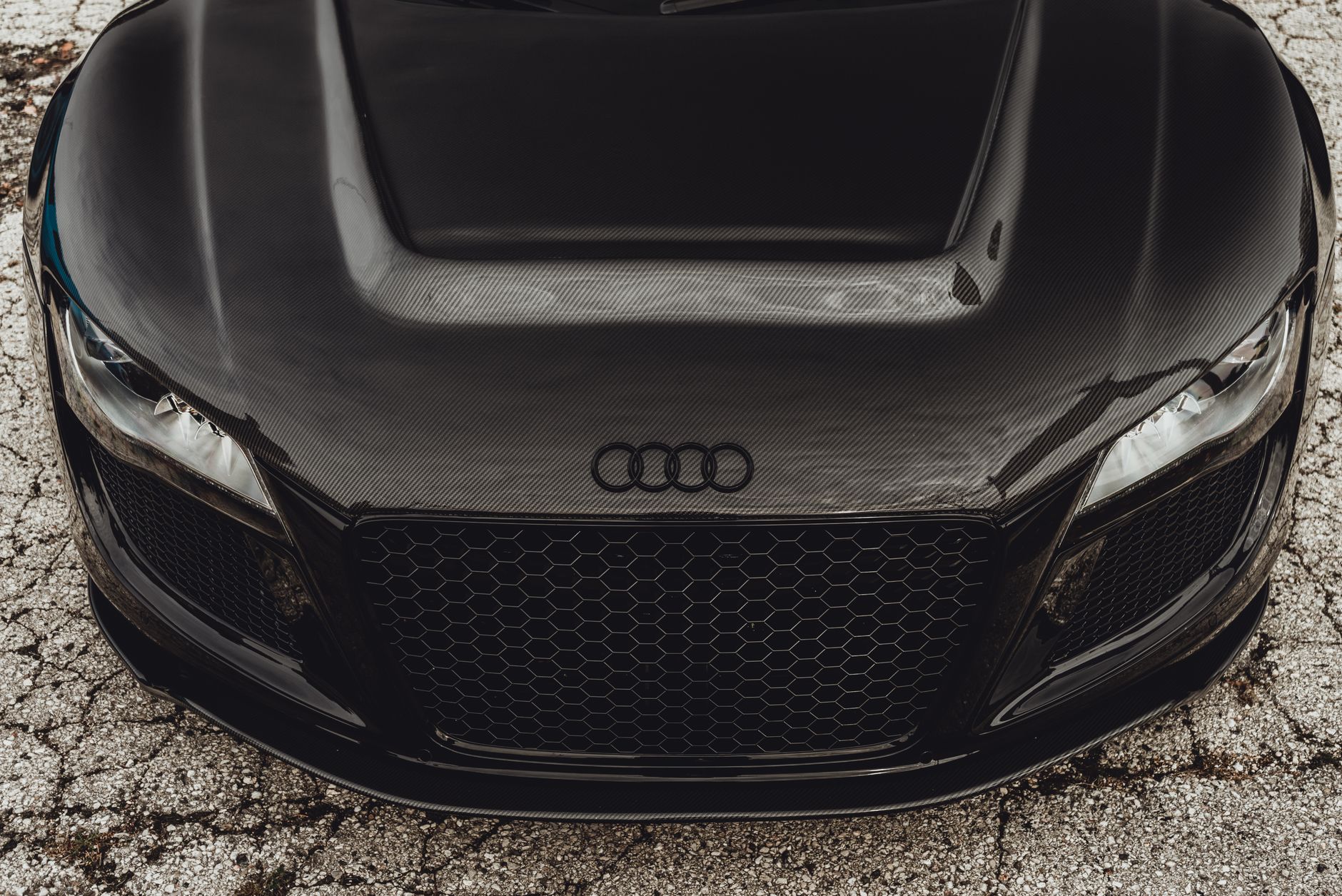 Detailed front view of a black Audi R8 supercar showcasing its carbon fiber hood and grille.