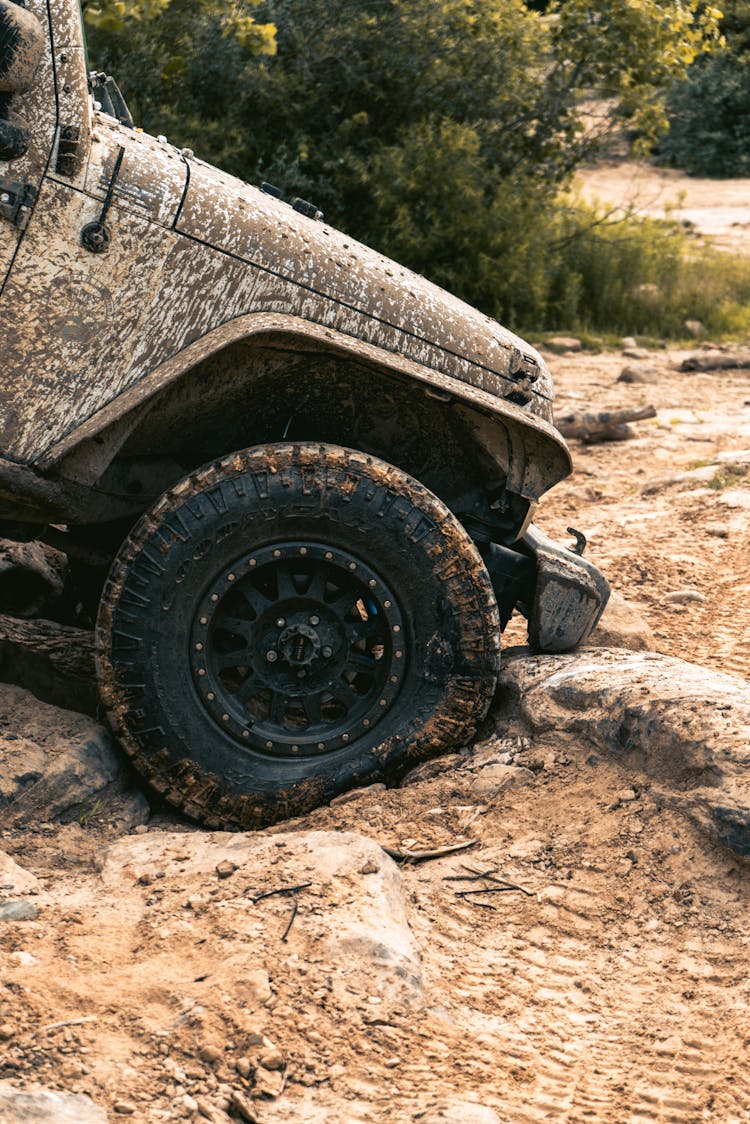Muddy Sport Utility Vehicle Driving On Big Rock