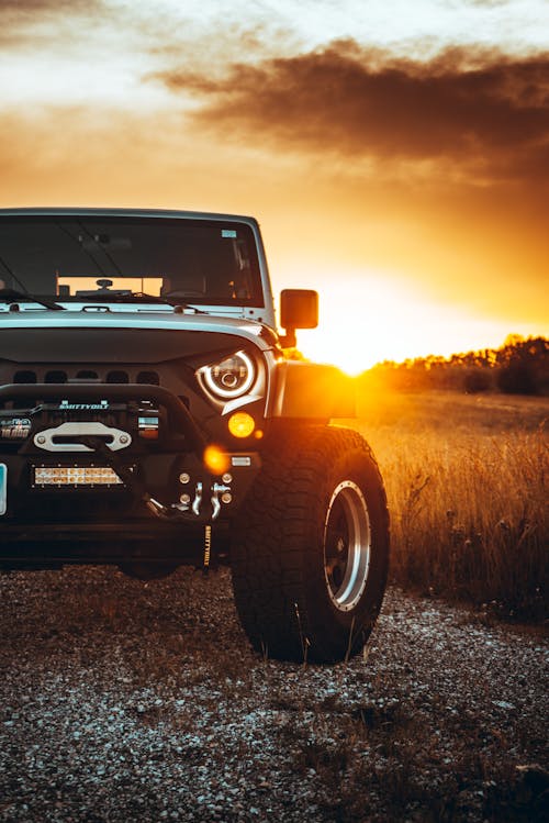 White Jeep Wrangler Parked on Grass Field During Sunset
