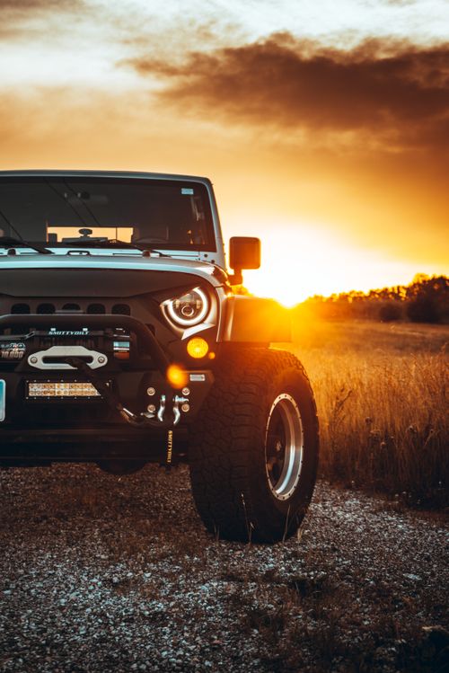 Free A rugged Jeep SUV parked on a dirt road during a vibrant sunset, highlighting adventure and exploration. Stock Photo