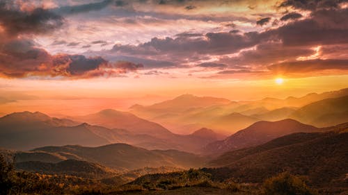 Free View of Sunrise Above Mountains with Dark Cloudy Sky Stock Photo