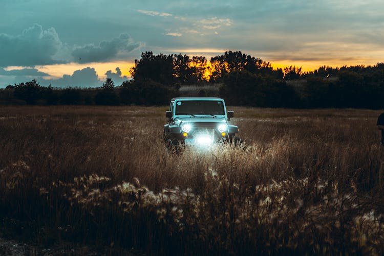 Jeep Driving On A Grass Field During Sunset