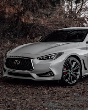 A white Infiniti car parked outdoors amidst autumn foliage, showcasing luxury and elegance.