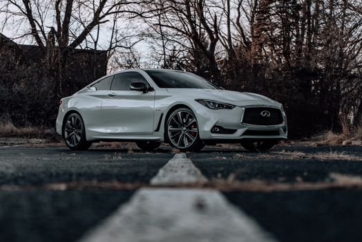 Low angle shot of a sleek white luxury sports car with stylish wheels parked outdoors.