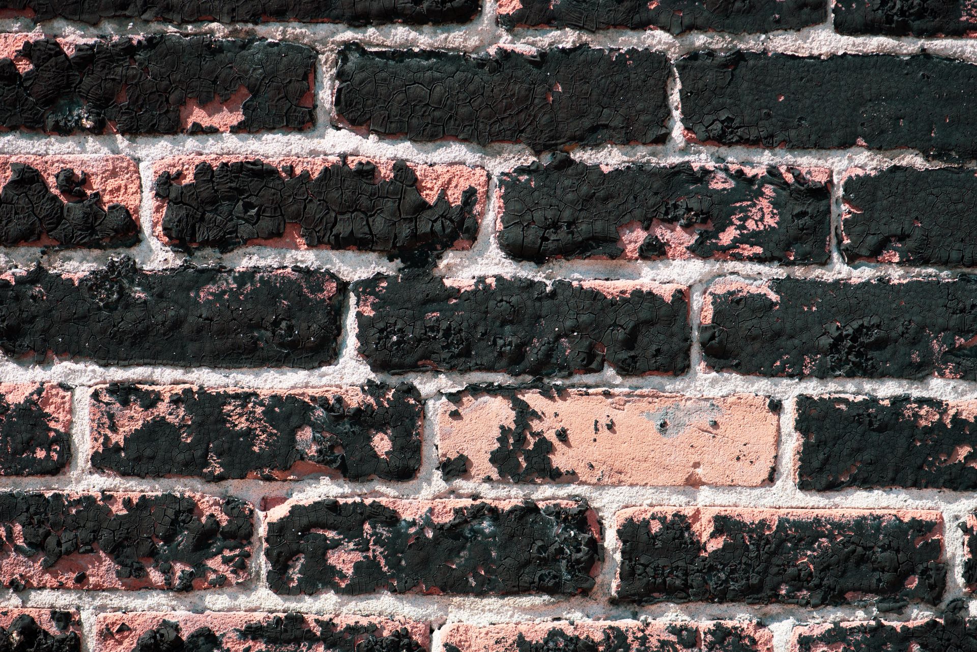 Detailed view of a weathered brick wall with peeling paint and rustic texture.