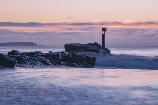 Stunning view of rocks and waves at sunset at Bournemouth, UK. Perfect for tranquil and nature themes.
