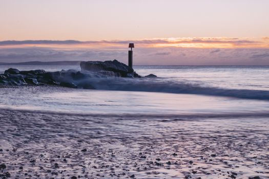 Tranquil scene of Bournemouth beach with soft waves and a stunning sunrise.