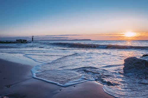 Человек, стоящий на берегу моря во время заката