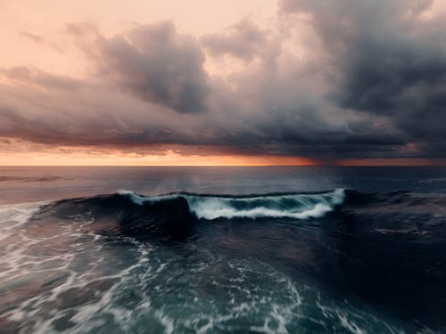 Gelombang Laut Di Bawah Langit Berawan Saat Matahari Terbenam