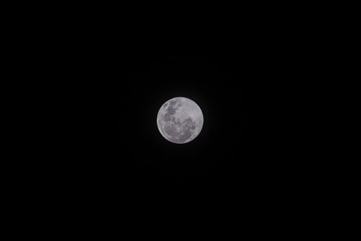 A stunning full moon against a dark, starless night sky.