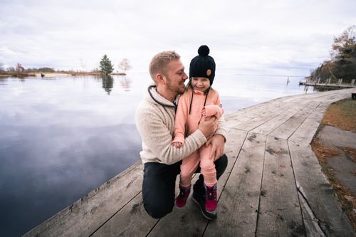 Free A father and daughter enjoy a loving moment by a scenic lake on a wooden pathway. Stock Photo