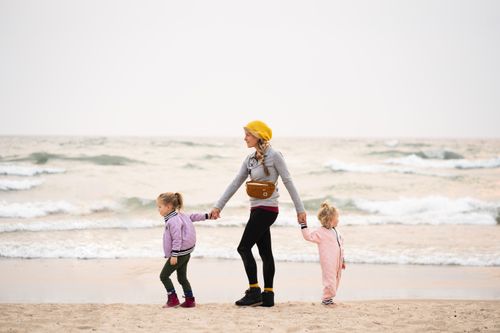 Free A mother walks hand-in-hand with two young daughters on Grand Haven Beach, Michigan. Stock Photo