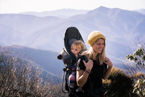 Woman in Black Shirt Carrying Her Daughter While Hiking