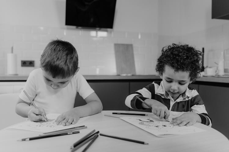 Two Kids Coloring A Drawing On White Paper