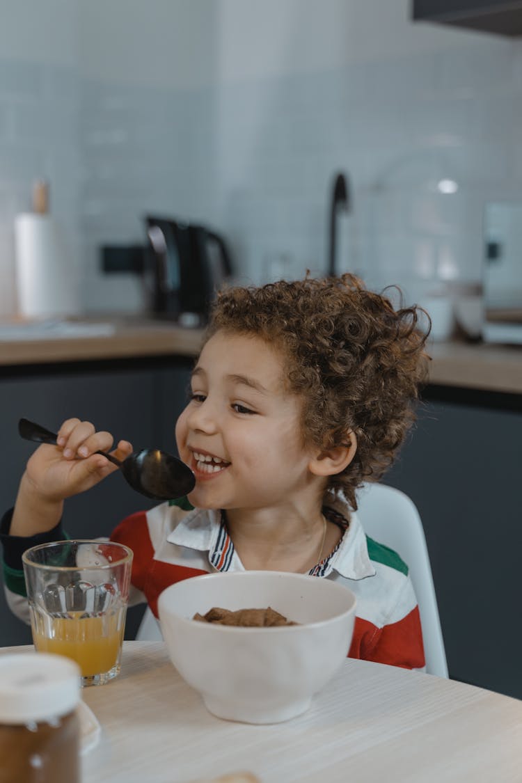 A Young Girl Smiling While Holding A Spoon