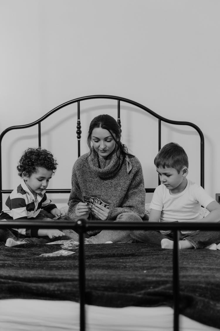 Woman And Two Boys Playing With Cards On Bed