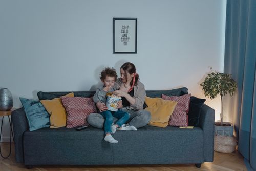 Free A mother and child enjoy snacks while relaxing together on a cozy couch. Stock Photo