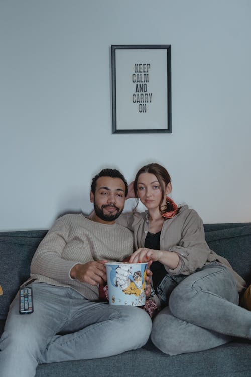 Free A Couple Sitting on the Sofa while Holding Popcorn  Stock Photo