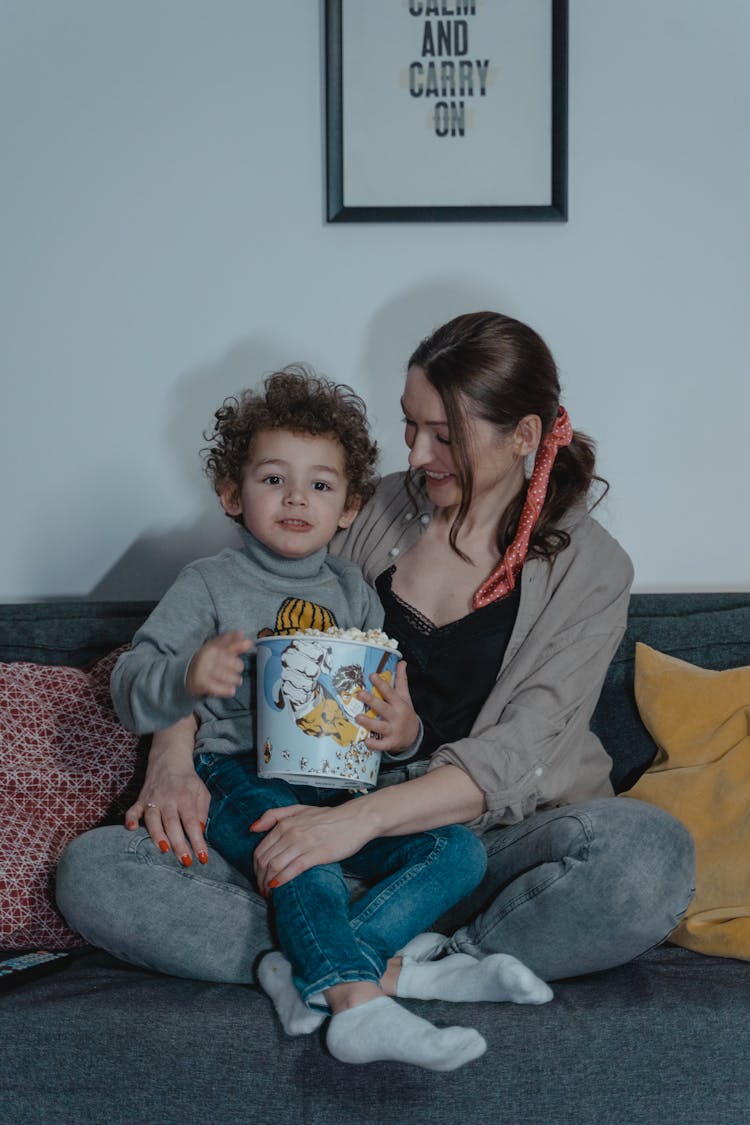 Woman And A Child Sitting On A Sofa Eating Popcorn