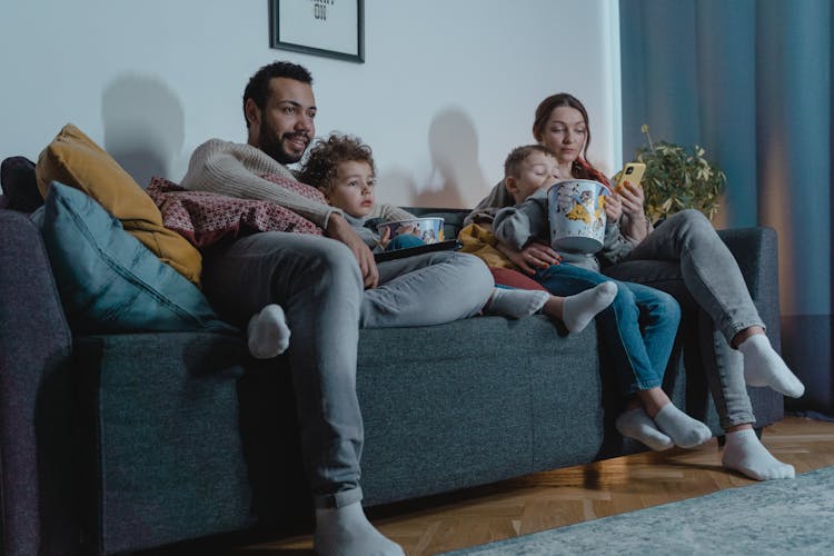 Family Sitting On A Sofa Eating Popcorn