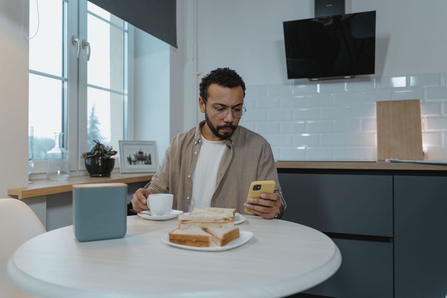 Man at breakfast table planning his day with his phone