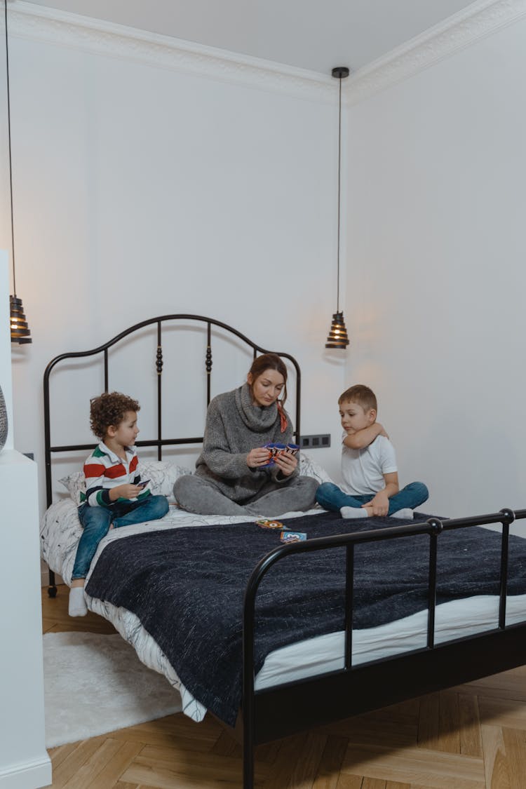 Woman And Two Boys Playing Cards On Bed