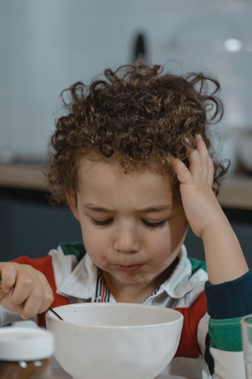 Close-up Photo of a Cute Child eating from a Ceramic Bowl 