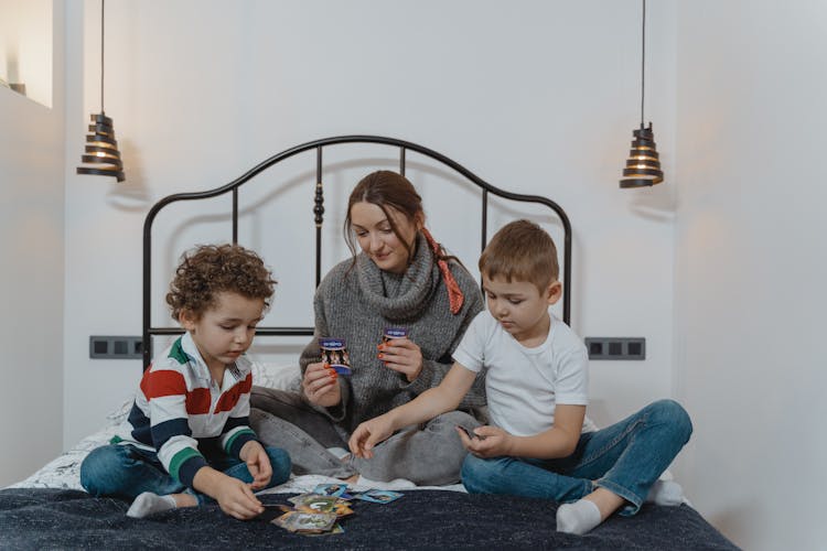 Mother And Kids Playing Cards On The Bed