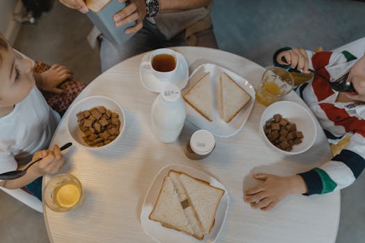 Children enjoying a breakfast with cereal and sliced bread at a cozy indoor dining table.