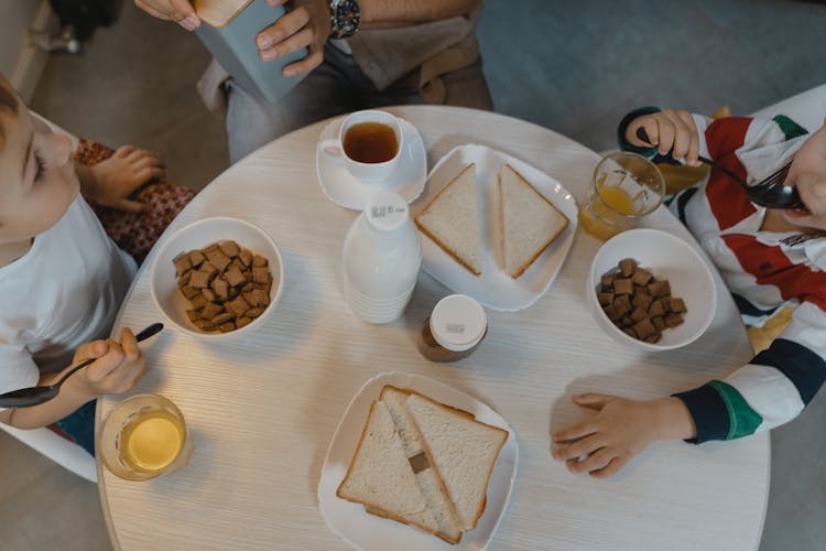 Children Eating Breakfast On A Round Table