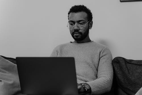 Grayscale Photography of a Man in Sweater Using Laptop Computer