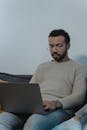 A Man in Brown Sweater Using a Laptop