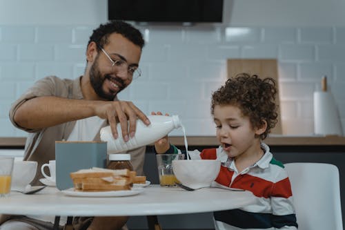 Free A Dad Pouring Milk on Son's Bowl Stock Photo